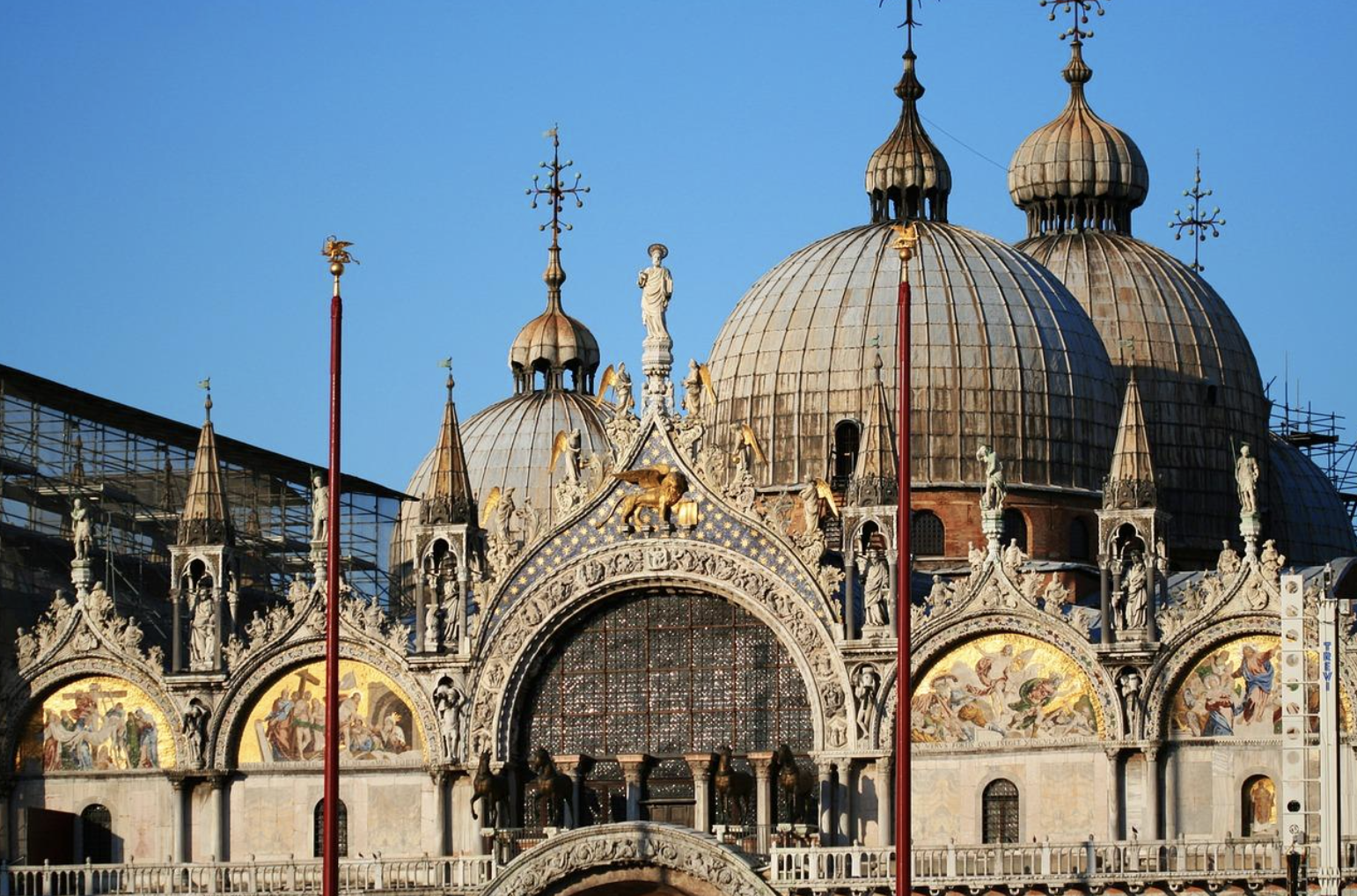 St. Mark's Basilica in Venice showcases its stunning architecture and intricate details under a clear blue sky.